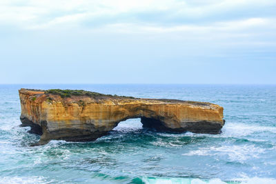Rock formation in sea against sky
