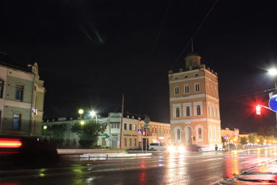 Illuminated buildings by street at night