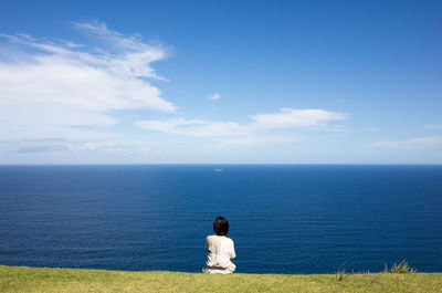 Rear view of woman looking at seascape against sky