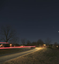 Light trails on road against sky at night