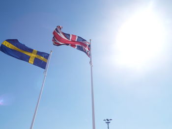 Low angle view of flags hanging against blue sky