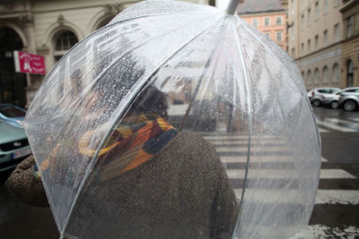 Reflection of man on wet street in city