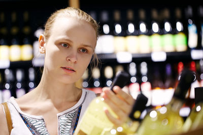 Woman holding wine bottle at supermarket