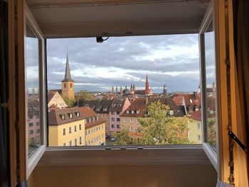 Buildings against sky seen through glass window