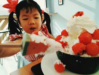 Close-up of cute girl holding cake on table