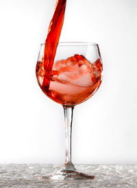 Close-up of wineglass on glass against white background