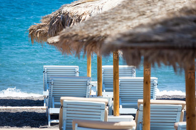 Empty chairs on beach against sea