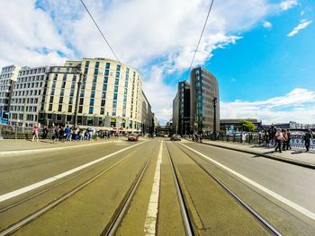 Road passing through city against cloudy sky