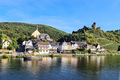 Houses by river and buildings against sky