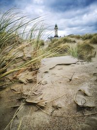 Lighthouse on field against sky