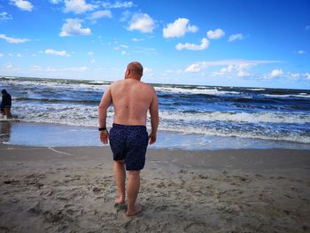 Rear view of shirtless man standing on beach