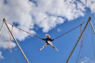 Low angle view of girl jumping against sky