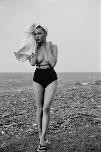 Woman standing at beach against sky