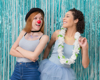 Happy friends standing against wall with decorations