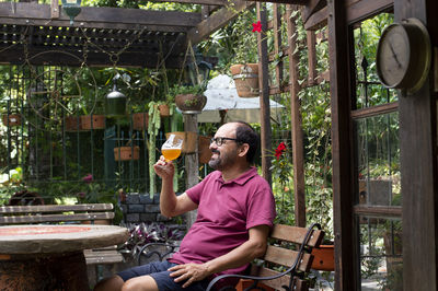 Man sitting outdoors amidst nature enjoying a glass of beer.