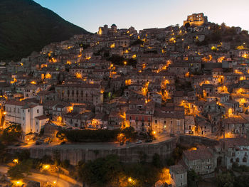 Illuminated cityscape against sky at dusk