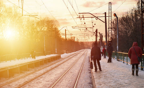 Rear view of people walking on railroad tracks in city
