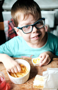 A boy in glasses eats french fries with cheese sauce, at home at the table. fast food for kids. 