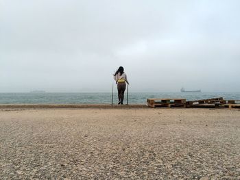 Rear view of woman walking at beach against sky