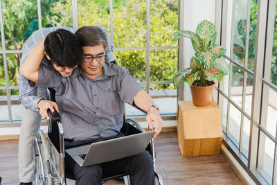 Businessman holding colleague head while using laptop in office