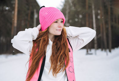 Portrait of smiling young woman standing against trees