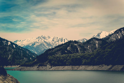 Scenic view of lake by snowcapped mountains against sky