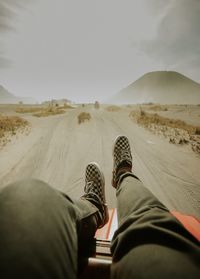 Low section of person on desert against sky