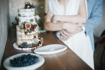 Midsection of couple with cake on table