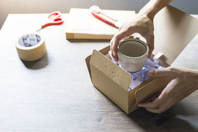 Midsection of woman holding coffee cup on table