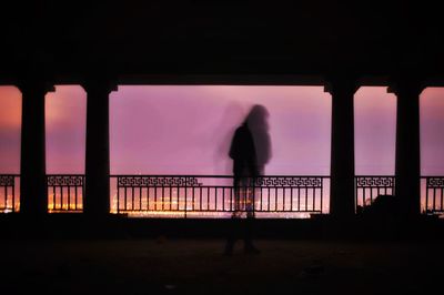 Silhouette woman standing on bridge against sky