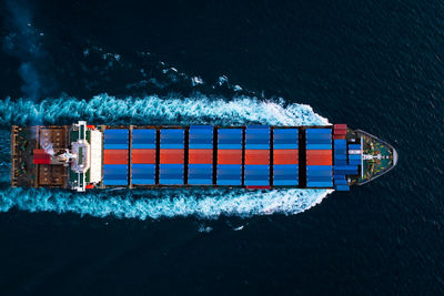 Aerial top view full speed container ship in the deep blue sea for cargo logistics import and export 