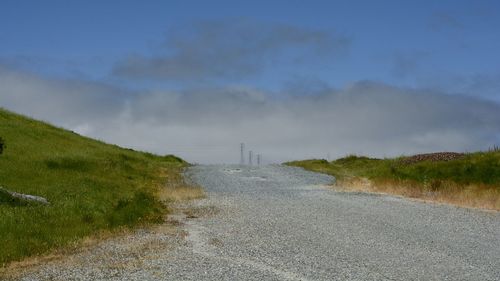 Road amidst field against sky