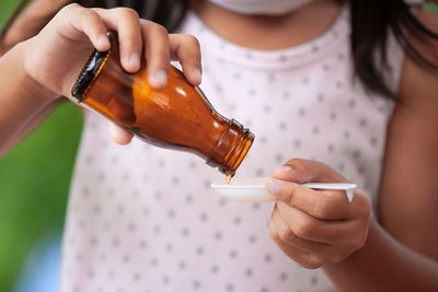 Midsection of girl pouring syrup in spoon
