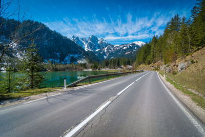 Road by trees and mountains against sky