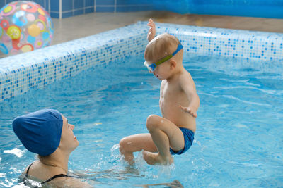 Toddler child learning to swim in indoor swimming pool with teacher. balancing in the water 