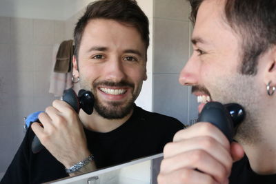 Portrait of a smiling young man holding camera