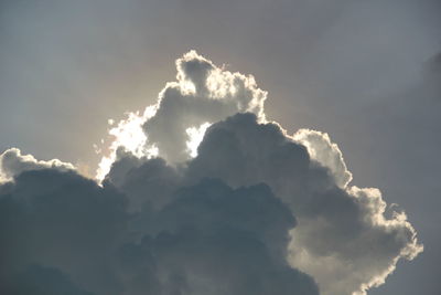 Low angle view of sunlight streaming through clouds