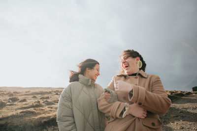 Female friends standing against sky