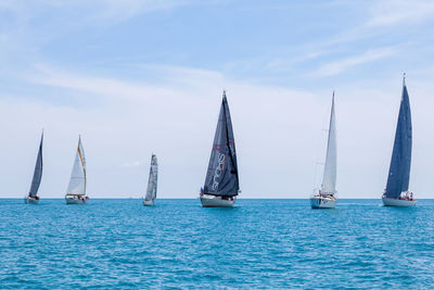 Sailboats sailing in sea against sky