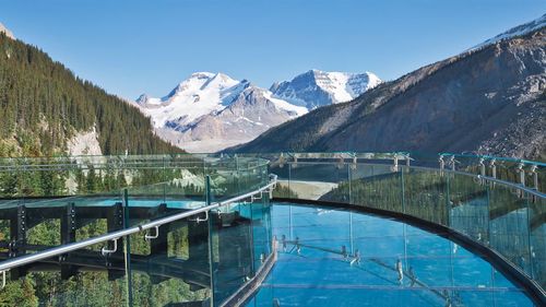 Scenic view of swimming pool by mountains against clear blue sky