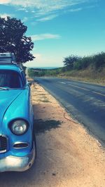 Close-up of car on road against blue sky