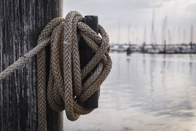 Close-up of rope tied to wooden post in sea