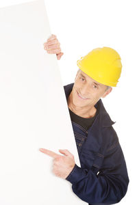 Construction worker wearing yellow hardhat holding blank placard against white background