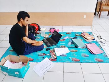 High angle view of mid adult man using laptop while sitting on blanket at home