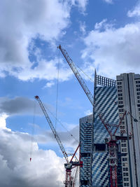 Low angle view of cranes against buildings