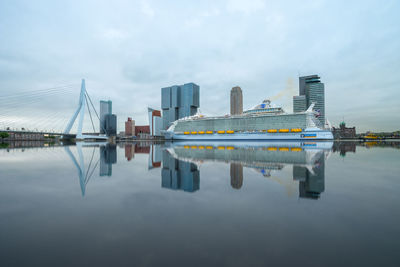 Reflection of modern buildings in river against sky