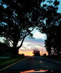 Road amidst trees against sky seen through car windshield