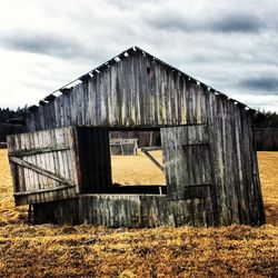 Barn on field against cloudy sky