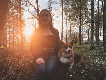 Woman sitting with dog in forest