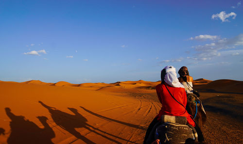 Rear view of woman riding motorcycle on desert